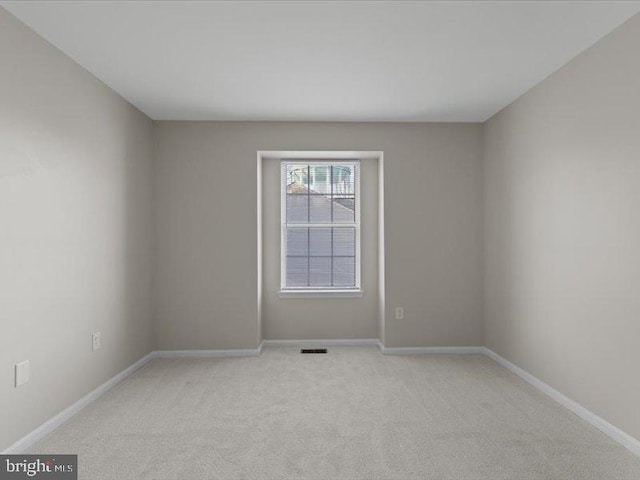 empty room featuring visible vents, light carpet, and baseboards