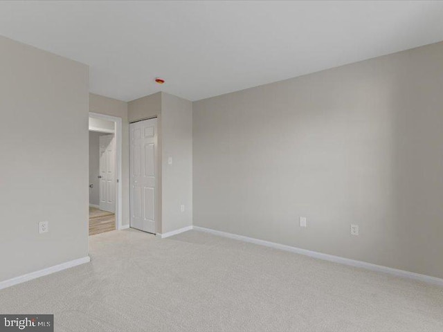 interior space featuring a closet, light carpet, and baseboards