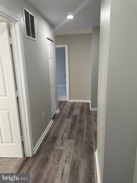 hallway featuring baseboards, visible vents, and wood finished floors