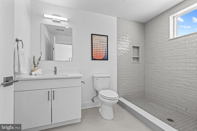 bathroom with vanity, tile patterned floors, toilet, and a tile shower