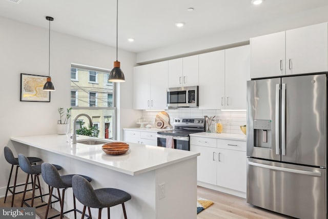 3205 N 35th St Unit 5, Philadelphia, PA 19129 - kitchen featuring appliances with stainless steel finishes, a sink, a kitchen bar, backsplash, and light wood finished floors