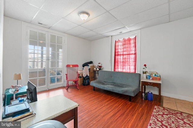 interior space with a drop ceiling, hardwood / wood-style floors, and a healthy amount of sunlight