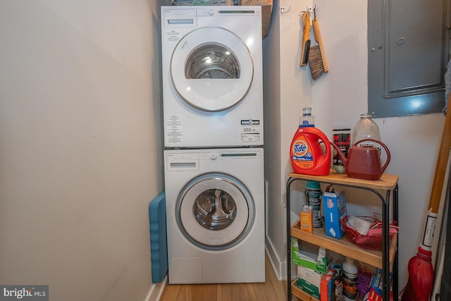 laundry area with stacked washer and clothes dryer, light hardwood / wood-style flooring, and electric panel