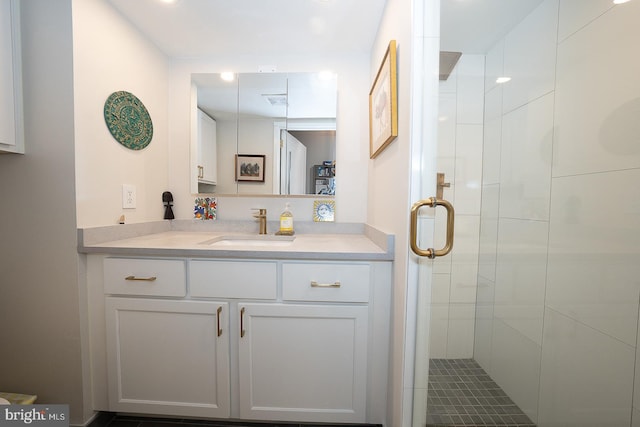 bathroom featuring a shower with shower door and vanity