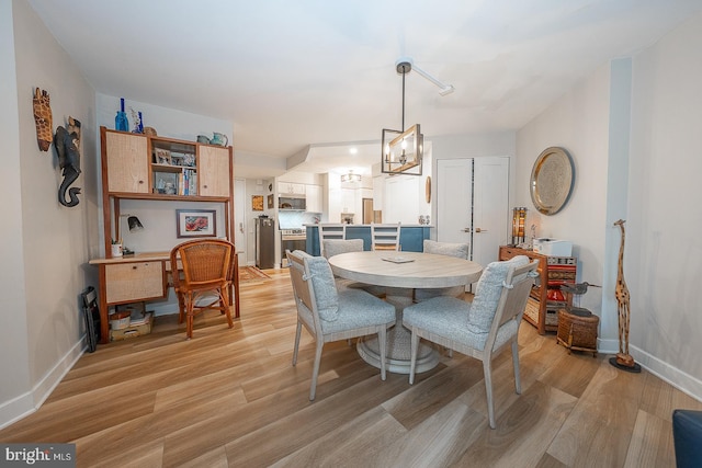 dining area with light wood-type flooring and a chandelier