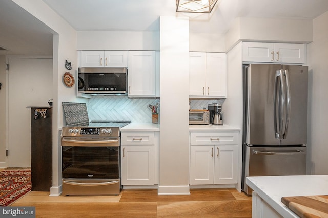 kitchen with light hardwood / wood-style floors, stainless steel appliances, white cabinetry, and decorative backsplash