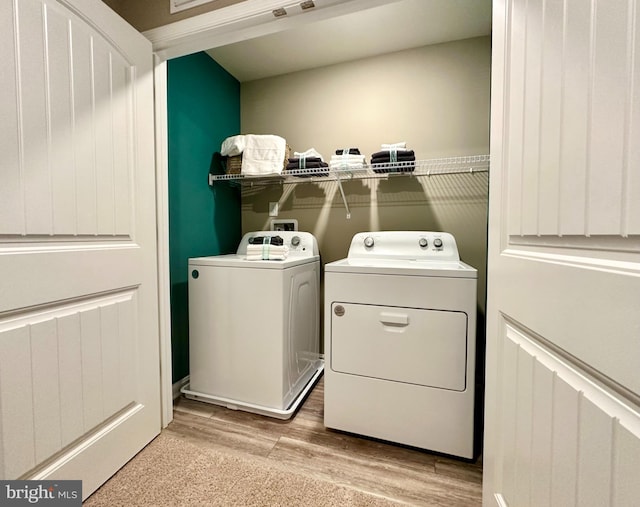 laundry area with washer and clothes dryer and light wood-type flooring