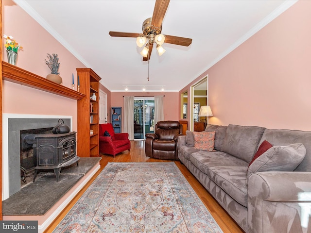 living room with rail lighting, crown molding, a wood stove, ceiling fan, and hardwood / wood-style floors