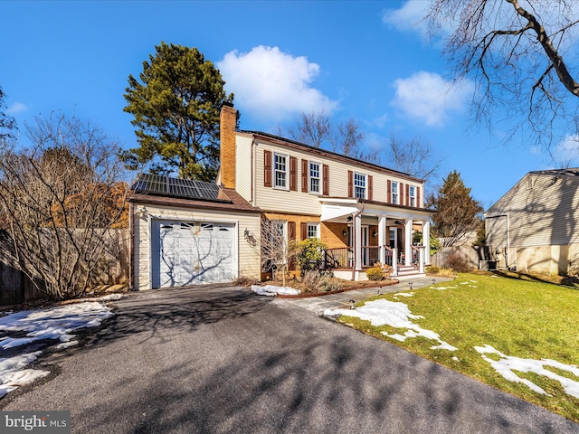 colonial inspired home with a front lawn, covered porch, and solar panels