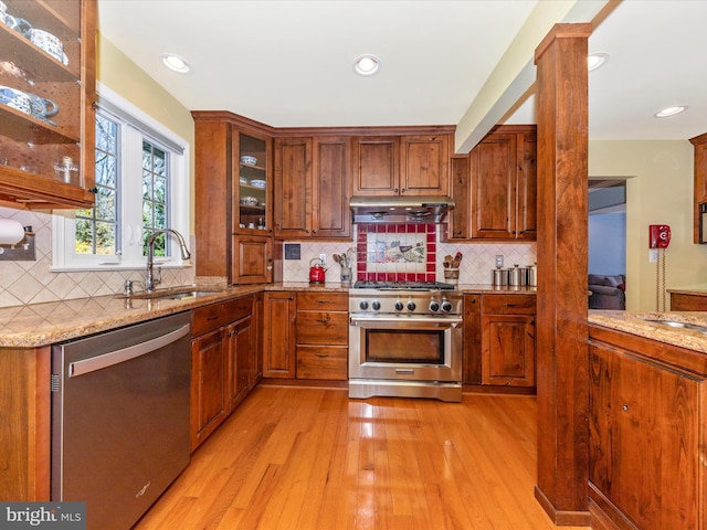 kitchen featuring sink, light hardwood / wood-style flooring, stainless steel appliances, light stone countertops, and backsplash