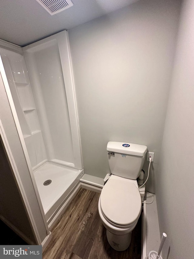 bathroom with toilet, hardwood / wood-style floors, and walk in shower