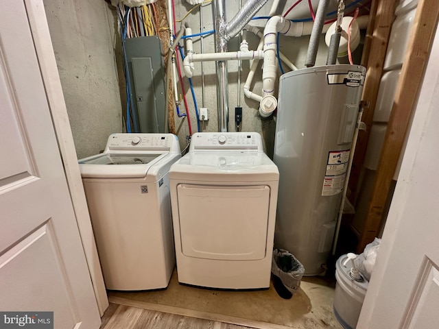 clothes washing area featuring washer and dryer, light hardwood / wood-style flooring, and water heater