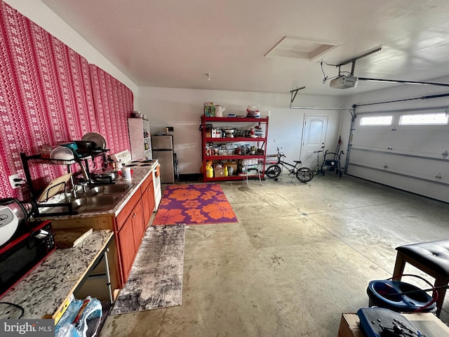 garage featuring a garage door opener, sink, and stainless steel refrigerator