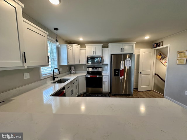 kitchen with dark wood-type flooring, white cabinets, sink, decorative light fixtures, and stainless steel appliances