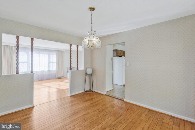 empty room with a chandelier and light hardwood / wood-style flooring