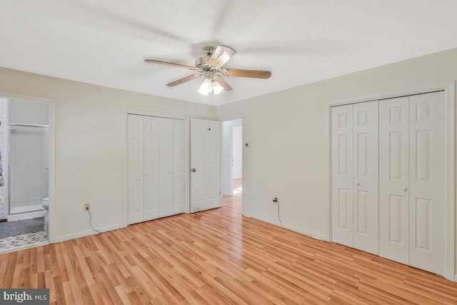 unfurnished bedroom with ceiling fan, light hardwood / wood-style floors, connected bathroom, and two closets