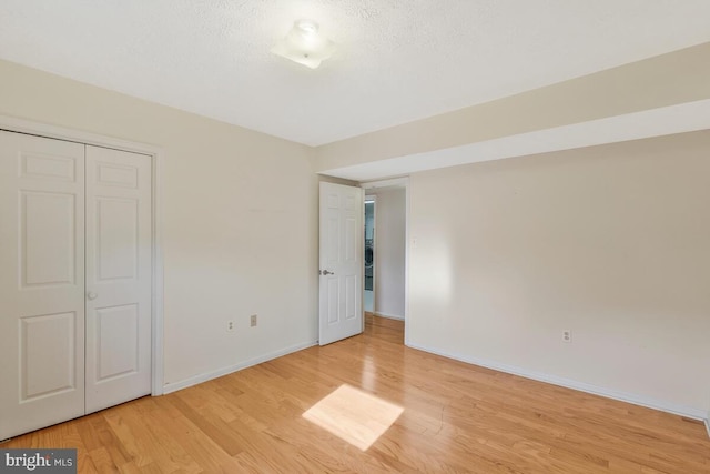 unfurnished bedroom with a textured ceiling, light hardwood / wood-style flooring, and a closet