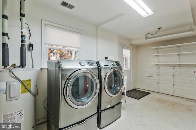 clothes washing area featuring independent washer and dryer, plenty of natural light, and water heater