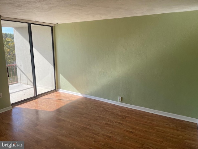 empty room featuring wood-type flooring, a healthy amount of sunlight, and a textured ceiling