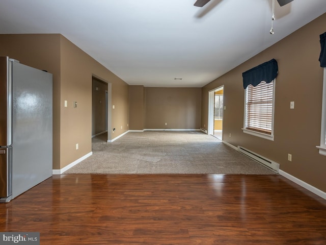 carpeted empty room with ceiling fan and a baseboard heating unit