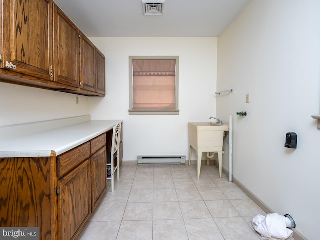 laundry room featuring cabinets, light tile patterned floors, and a baseboard heating unit