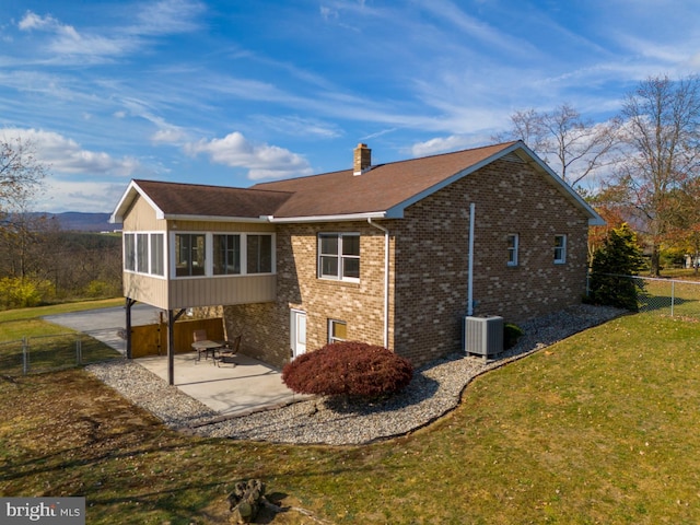 back of property with central AC unit, a yard, a sunroom, and a patio area