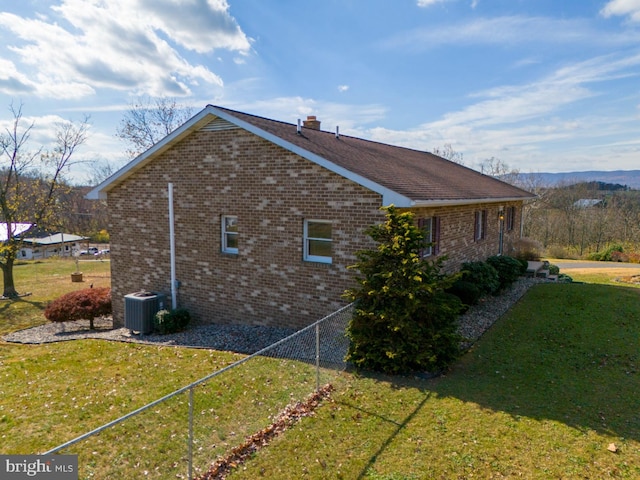 view of side of home with central AC unit and a yard