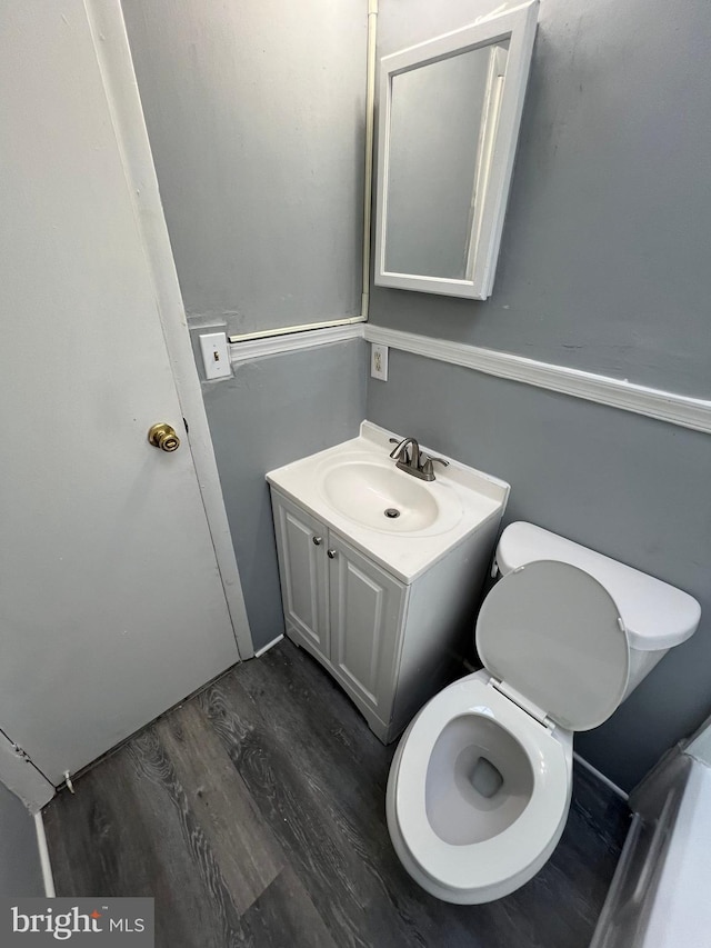 bathroom with wood-type flooring, toilet, and vanity