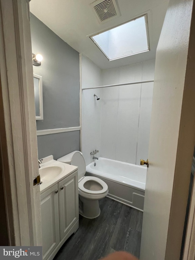 full bathroom featuring toilet, hardwood / wood-style floors, vanity, bathing tub / shower combination, and a skylight