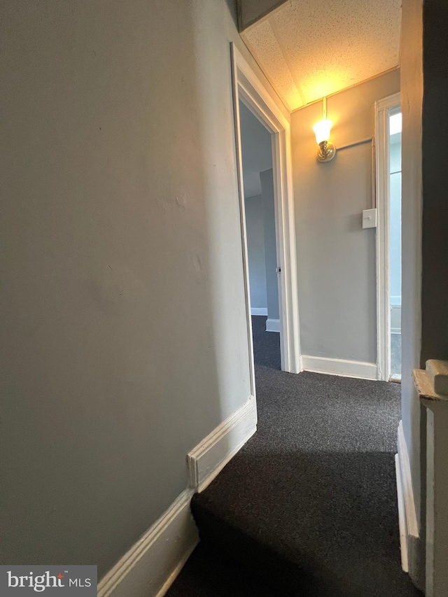 hall with a textured ceiling and carpet flooring