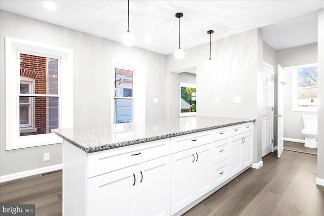 kitchen with white cabinetry, dark hardwood / wood-style flooring, pendant lighting, and light stone counters