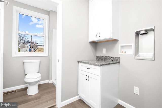 interior space featuring white cabinets, wood-type flooring, and stone countertops