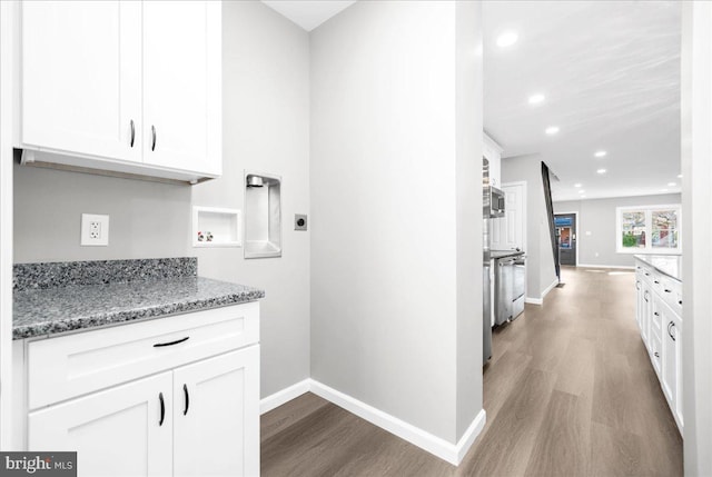 kitchen with white cabinets, hardwood / wood-style flooring, and stone counters