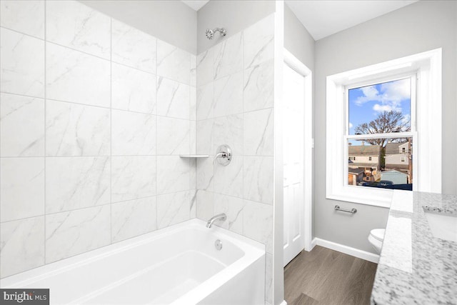 bathroom featuring hardwood / wood-style flooring, toilet, and tiled shower / bath