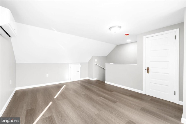 bonus room featuring a wall mounted air conditioner, wood-type flooring, and lofted ceiling