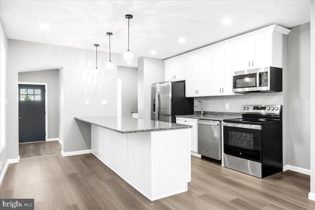 kitchen with pendant lighting, light wood-type flooring, white cabinetry, and appliances with stainless steel finishes