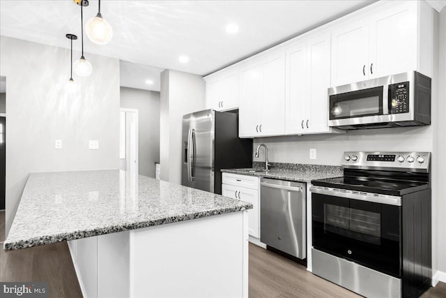 kitchen featuring white cabinets, light wood-type flooring, decorative light fixtures, light stone counters, and stainless steel appliances