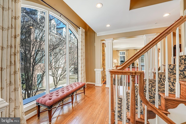 interior space with light wood-type flooring, a wealth of natural light, ornamental molding, and ornate columns