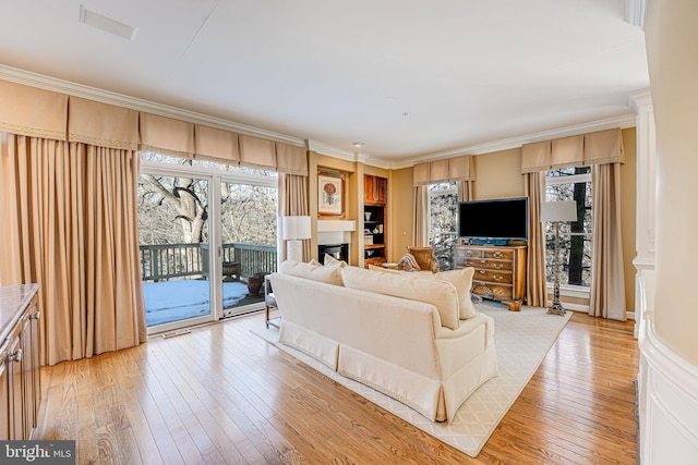 living room featuring light hardwood / wood-style floors, plenty of natural light, and crown molding