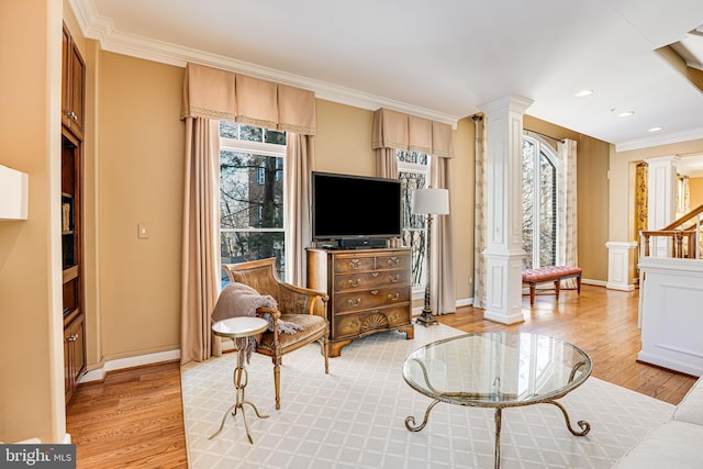 living room featuring light wood-type flooring, ornate columns, and plenty of natural light