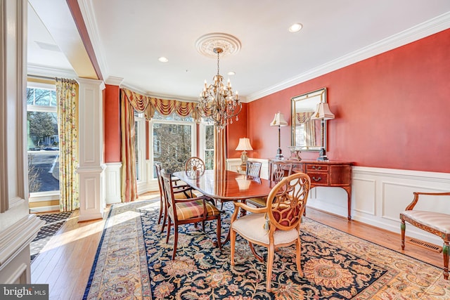 dining space featuring decorative columns, plenty of natural light, light hardwood / wood-style flooring, and ornamental molding