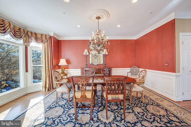 dining space with crown molding, light hardwood / wood-style floors, and an inviting chandelier