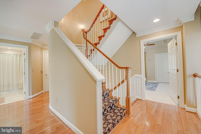 staircase with ornamental molding and hardwood / wood-style floors