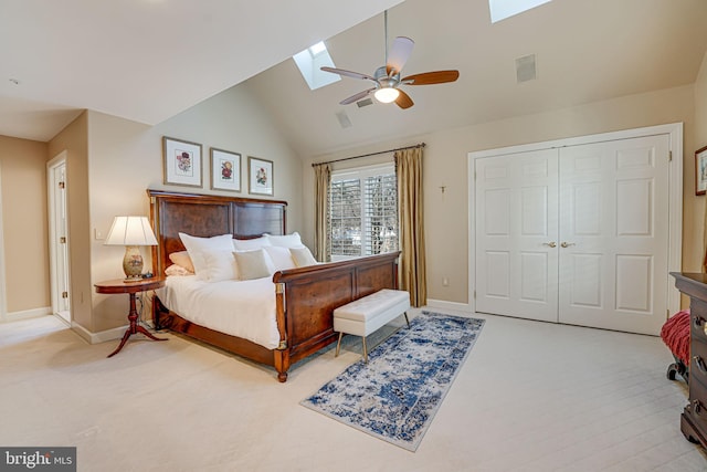 carpeted bedroom with vaulted ceiling with skylight, a closet, and ceiling fan