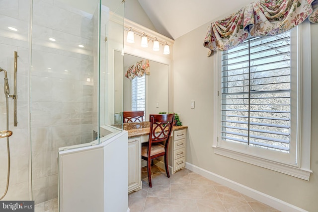 bathroom with tile patterned floors, a tile shower, vanity, and lofted ceiling