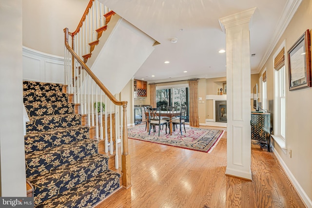 stairs with hardwood / wood-style flooring, decorative columns, and ornamental molding