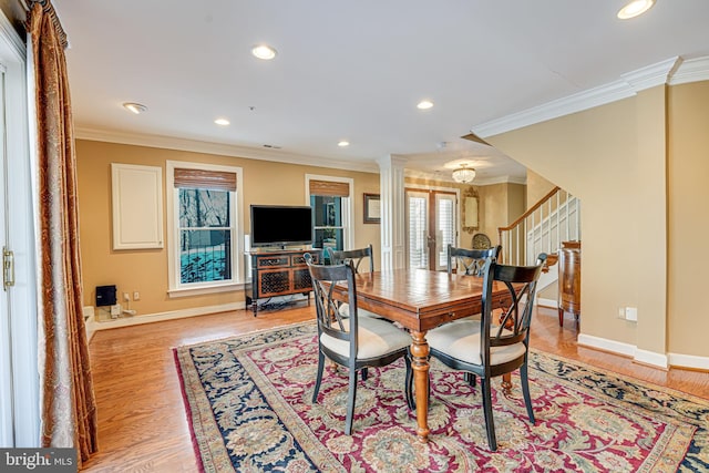 dining space featuring light hardwood / wood-style floors, ornate columns, and ornamental molding