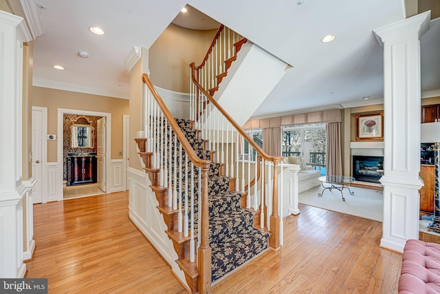 stairway featuring decorative columns, hardwood / wood-style flooring, and crown molding