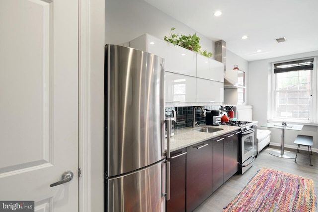 kitchen with dark brown cabinetry, sink, light hardwood / wood-style floors, white cabinets, and appliances with stainless steel finishes