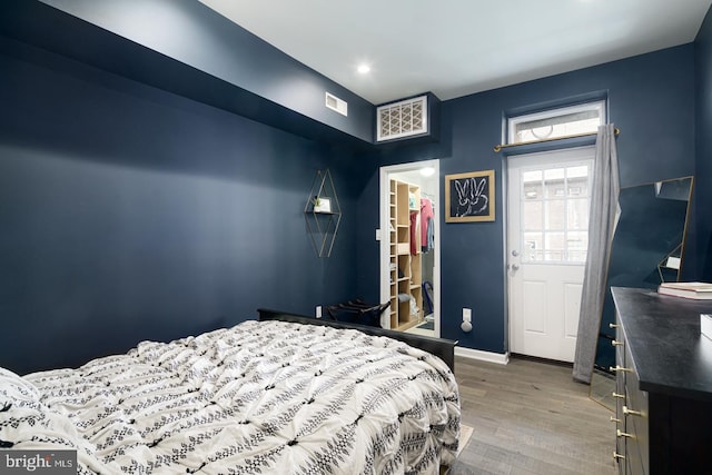 bedroom with wood-type flooring, a spacious closet, and a closet